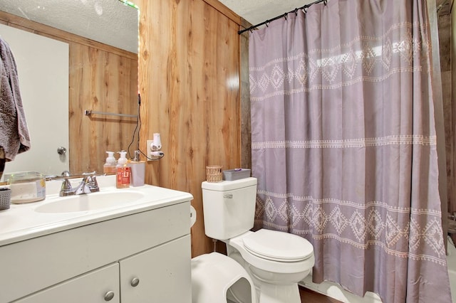 bathroom with vanity, toilet, a textured ceiling, and wood walls