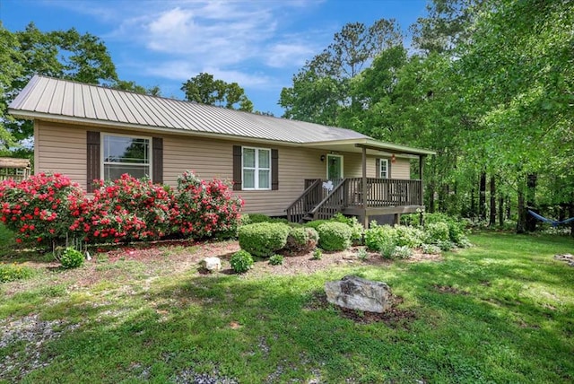 ranch-style home featuring a deck, metal roof, and a front yard