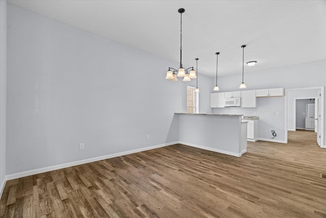 429 Glenwood Ave, Dalton, GA 30721 - kitchen featuring white microwave, white cabinetry, wood finished floors, a chandelier, and a peninsula