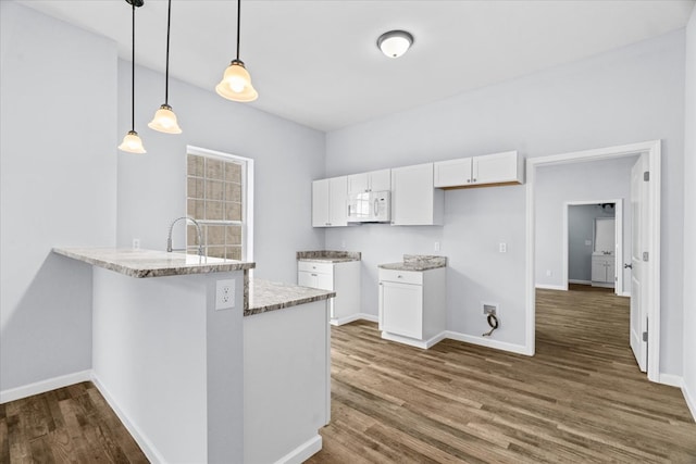 429 Glenwood Ave, Dalton, GA 30721 - kitchen featuring white microwave, white cabinetry, light stone counters, a peninsula, and dark wood finished floors