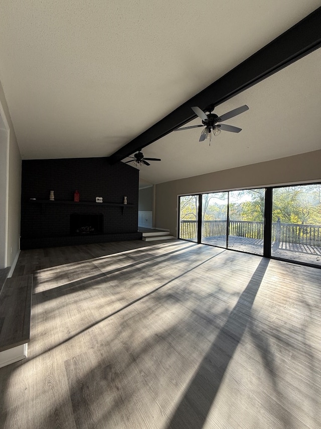 unfurnished living room with wood-type flooring, vaulted ceiling with beams, and a textured ceiling