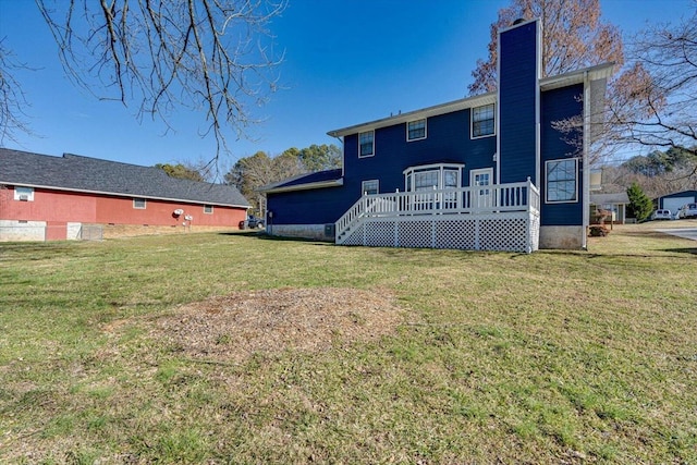 back of house with a chimney, a deck, and a lawn