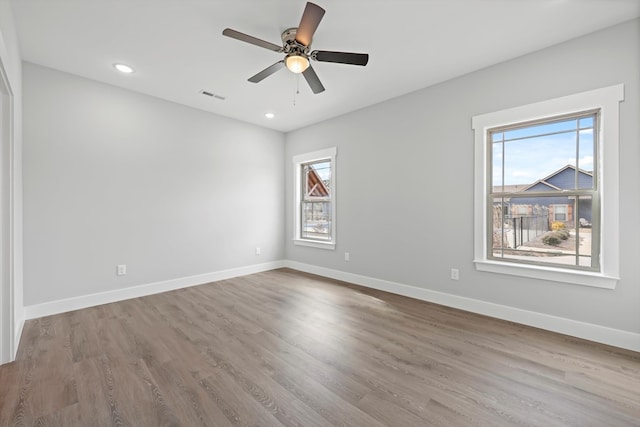empty room with a ceiling fan, visible vents, light wood finished floors, and baseboards
