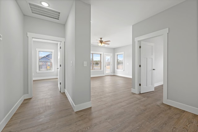 hallway featuring light wood-type flooring, baseboards, and visible vents