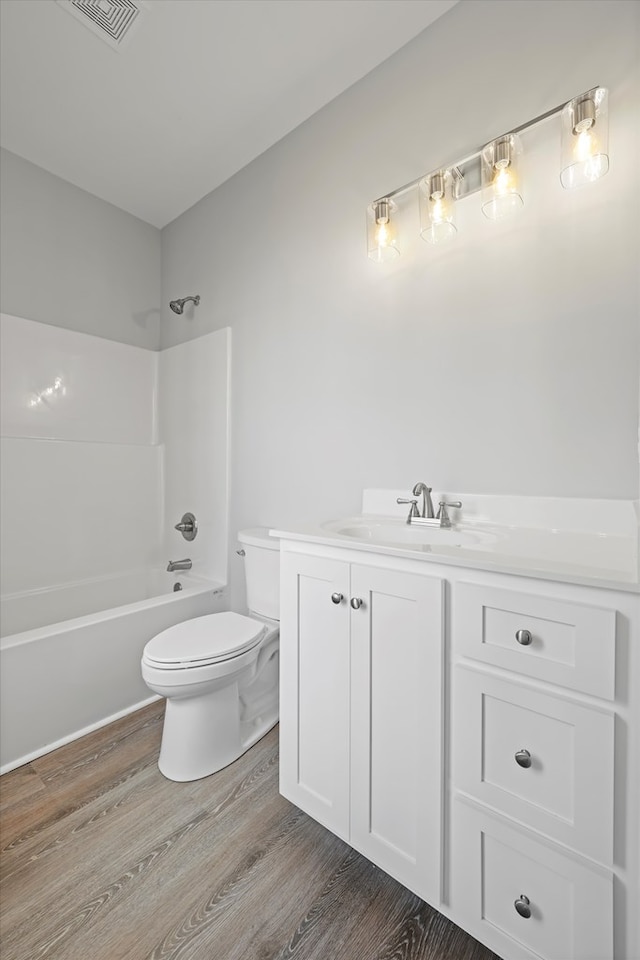 bathroom with toilet, shower / bath combination, wood finished floors, and vanity