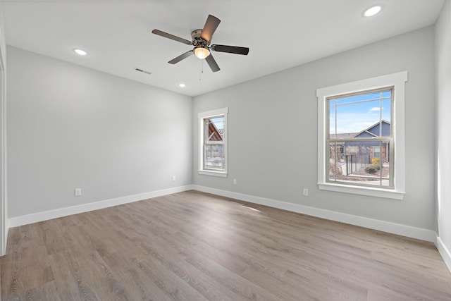 spare room with light wood-style flooring, baseboards, and a wealth of natural light