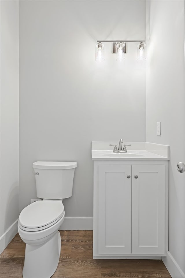 bathroom featuring baseboards, vanity, toilet, and wood finished floors