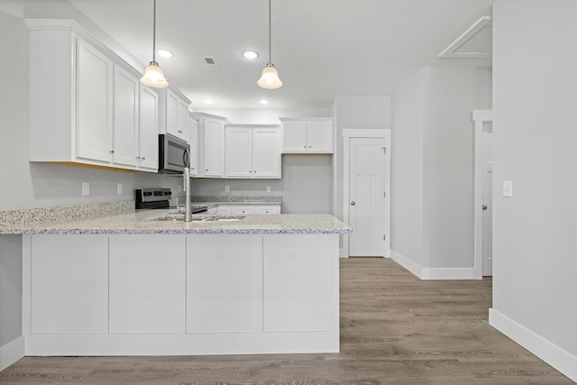 kitchen with white cabinets, appliances with stainless steel finishes, decorative light fixtures, a peninsula, and light stone countertops