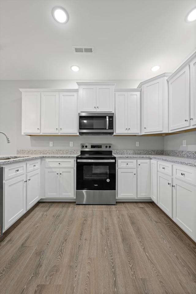 kitchen featuring stainless steel appliances, white cabinetry, and a sink