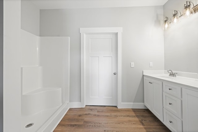 full bathroom featuring baseboards, wood finished floors, and vanity