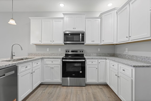 kitchen featuring stainless steel appliances, white cabinetry, a sink, and light stone countertops