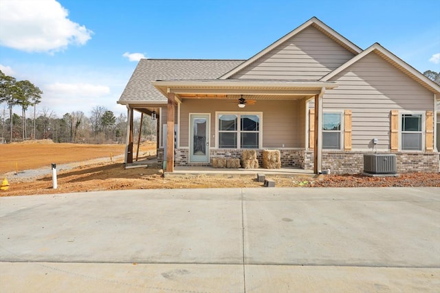 view of front of home featuring a shingled roof, a ceiling fan, covered porch, central air condition unit, and brick siding