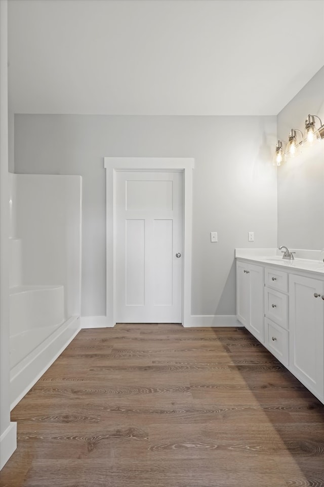 full bathroom featuring wood finished floors, vanity, and baseboards