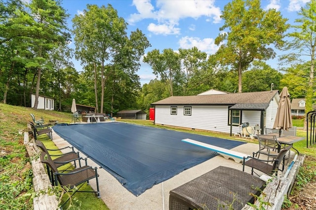 view of swimming pool with a patio, a diving board, and a shed