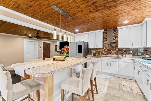 kitchen with white cabinetry, wall chimney range hood, and a kitchen breakfast bar