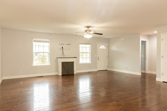 unfurnished living room featuring dark wood-type flooring and ceiling fan