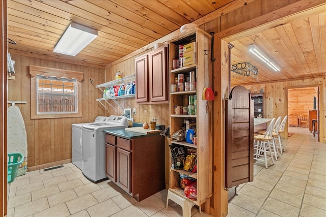 washroom with light tile patterned floors, wood ceiling, cabinets, separate washer and dryer, and wood walls