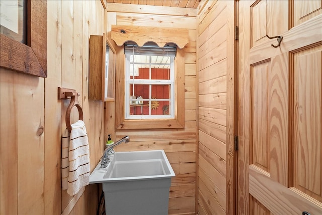 bathroom featuring sink and wood walls