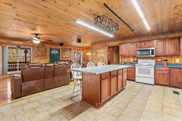 kitchen featuring wood ceiling, white range with electric cooktop, a breakfast bar, and a center island