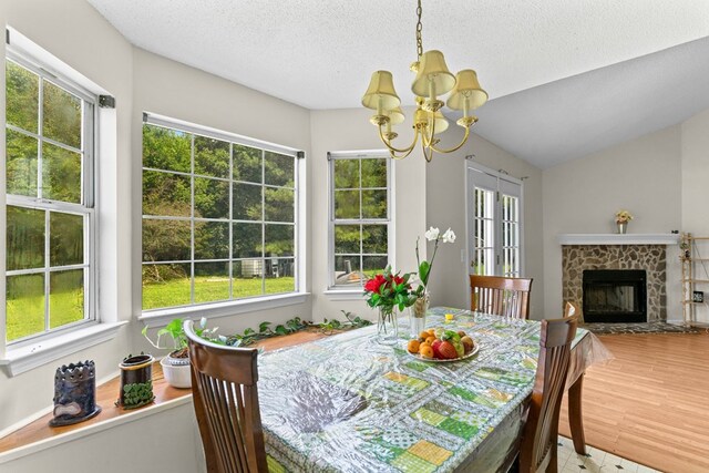 163 Shawn Ln, Chatsworth, GA 30705 - dining space featuring a chandelier, a textured ceiling, a stone fireplace, and lofted ceiling