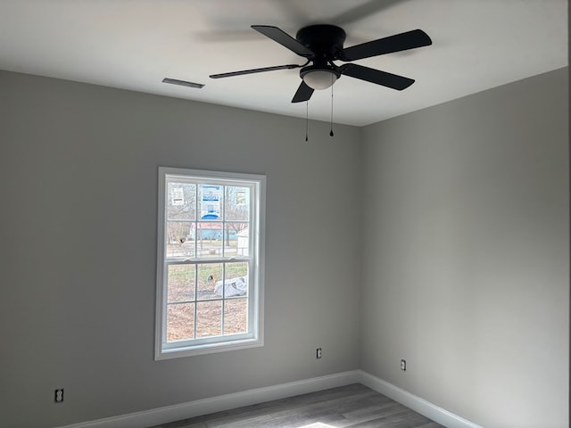 unfurnished room featuring a wealth of natural light, baseboards, light wood-style floors, and ceiling fan