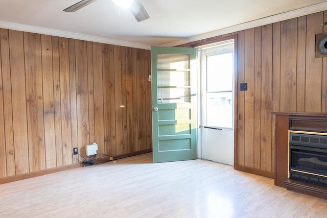 unfurnished living room featuring ornamental molding, light hardwood / wood-style floors, ceiling fan, and wood walls