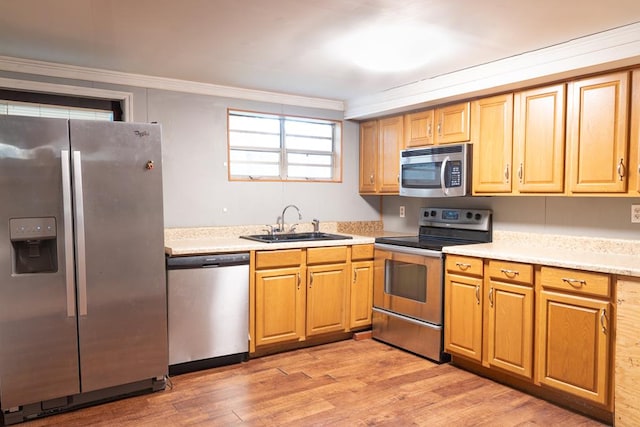 kitchen featuring sink, crown molding, light wood-type flooring, and appliances with stainless steel finishes