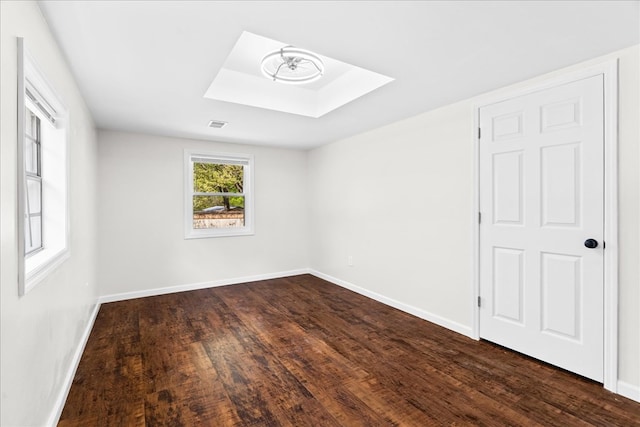 unfurnished room featuring a skylight, baseboards, and dark wood-style flooring