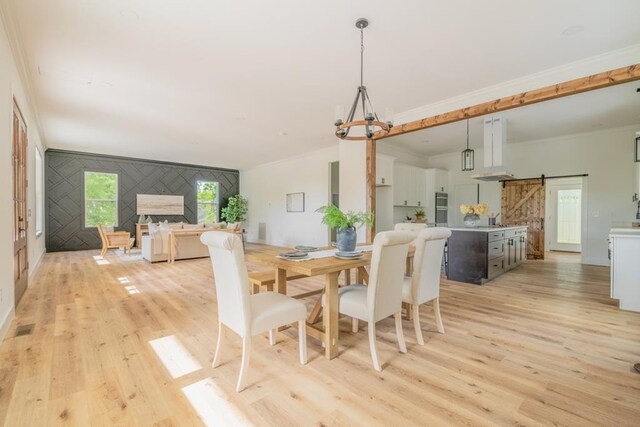 209 Crest Dr, Rocky Face, GA 30740 - dining area with light wood-style floors, a barn door, an accent wall, and crown molding