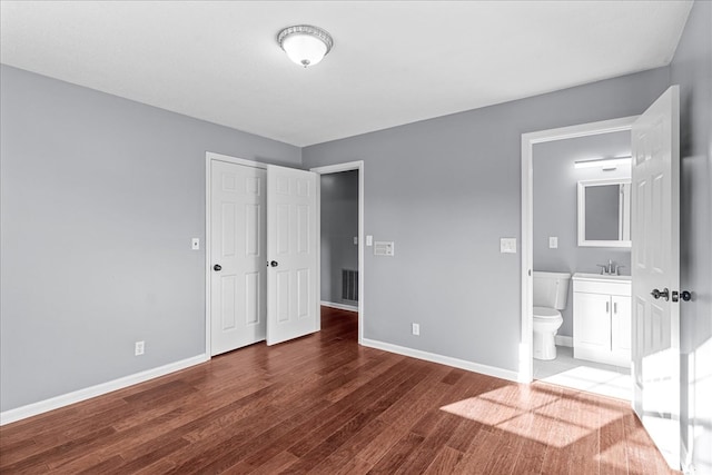 unfurnished bedroom featuring sink, wood-type flooring, a closet, and ensuite bathroom