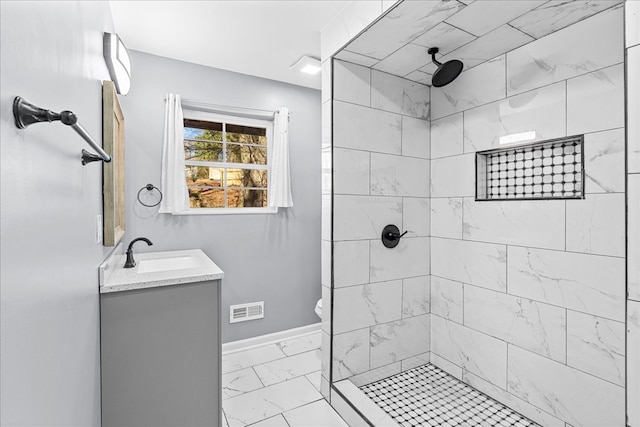 bathroom with tiled shower, vanity, and toilet