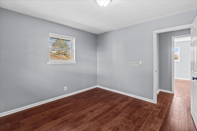 unfurnished room with dark wood-type flooring, a textured ceiling, and a wealth of natural light