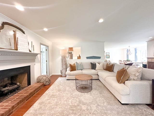 living room featuring crown molding, recessed lighting, a fireplace with raised hearth, and wood finished floors