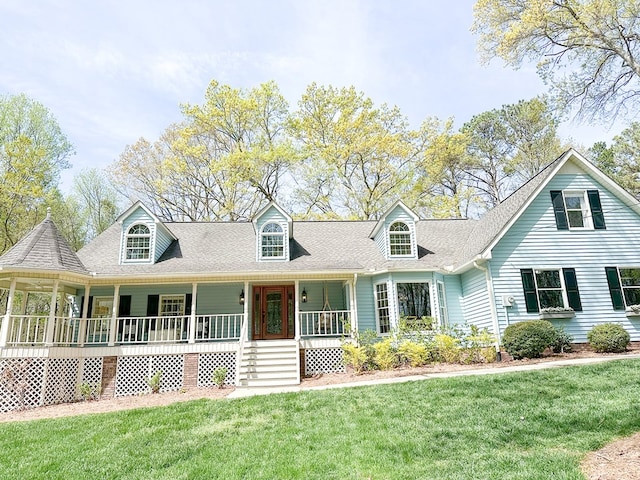 new england style home featuring roof with shingles, a front yard, and a porch