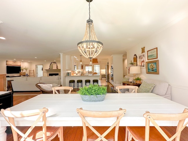 dining area featuring wood finished floors, a fireplace, a notable chandelier, and recessed lighting