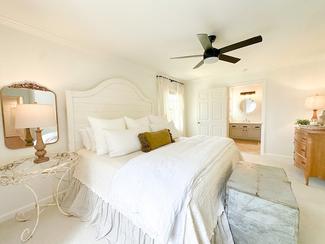 bedroom featuring baseboards, ornamental molding, ensuite bathroom, a ceiling fan, and light colored carpet