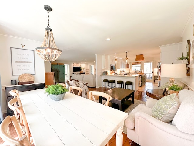 dining room featuring recessed lighting, light wood finished floors, a notable chandelier, and crown molding
