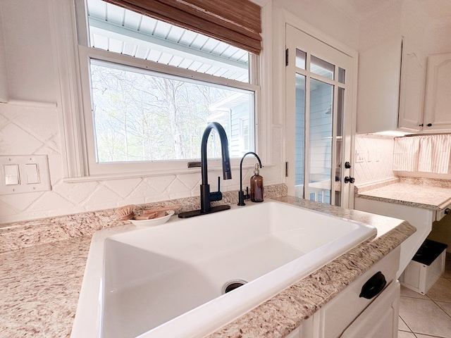 room details with white cabinetry, a sink, and backsplash