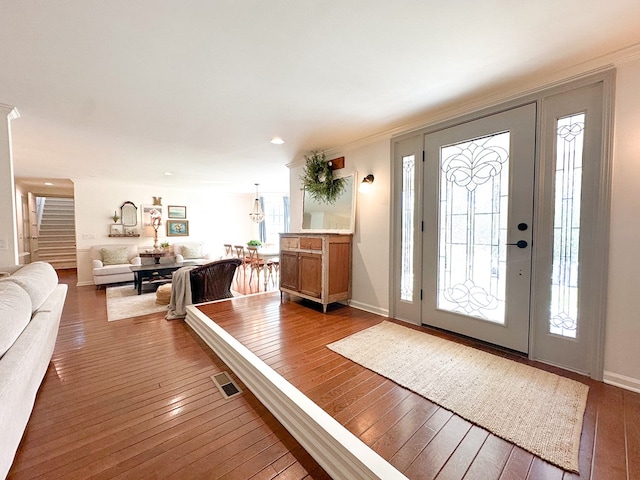 foyer featuring visible vents, baseboards, ornamental molding, stairs, and hardwood / wood-style floors