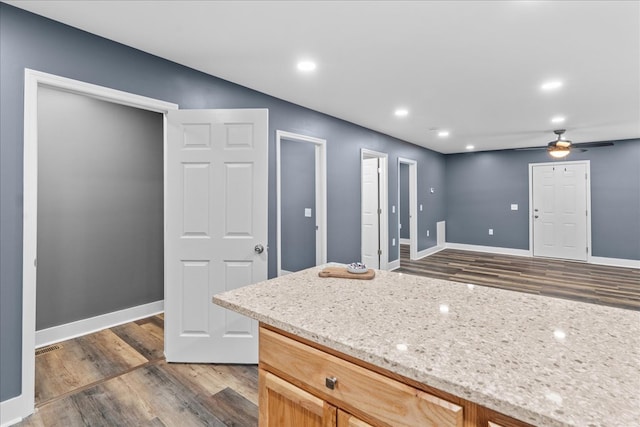 kitchen with light stone countertops, dark hardwood / wood-style floors, and ceiling fan