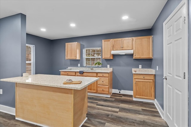 kitchen featuring light stone countertops, a center island, light brown cabinetry, and dark hardwood / wood-style flooring