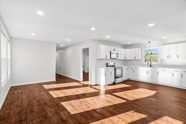kitchen featuring light countertops, stainless steel appliances, recessed lighting, dark wood finished floors, and a sink