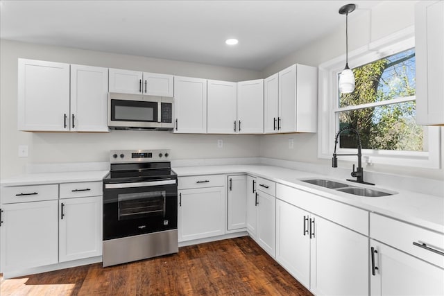 kitchen featuring white cabinets, light countertops, appliances with stainless steel finishes, a sink, and dark wood-style floors