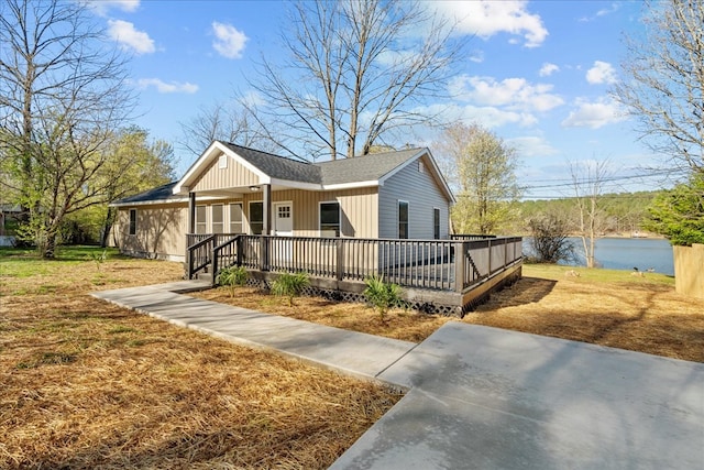 view of front of home featuring a front yard, a water view, and roof with shingles