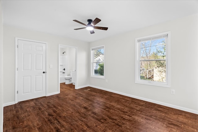 unfurnished bedroom with baseboards, dark wood-style floors, ceiling fan, and connected bathroom