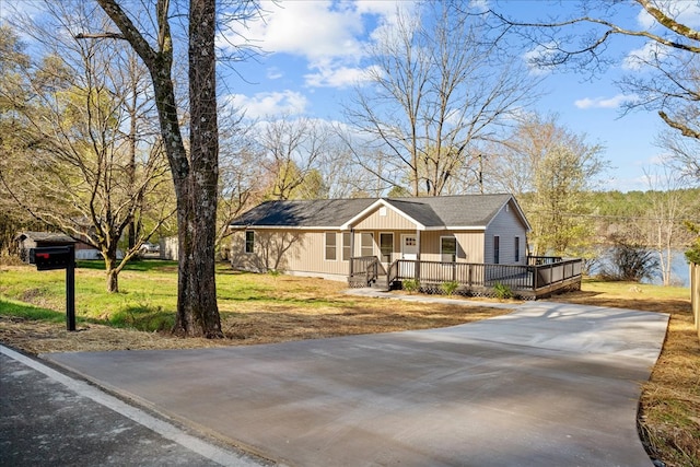 view of front facade with a porch, a front yard, and concrete driveway