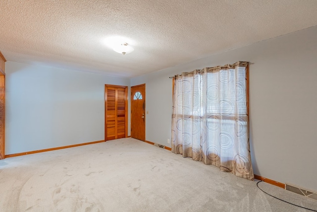 carpeted empty room featuring a textured ceiling