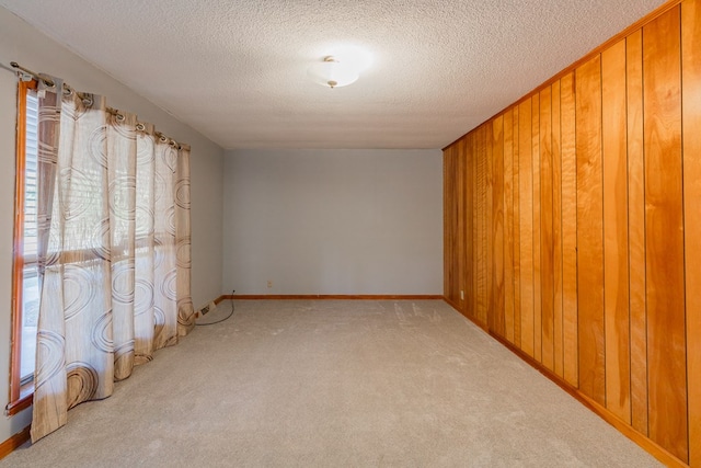 carpeted empty room with a textured ceiling and wood walls