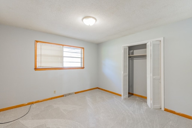 unfurnished bedroom with light colored carpet, a textured ceiling, and a closet