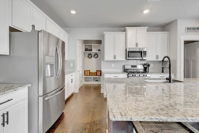 kitchen featuring a sink, appliances with stainless steel finishes, white cabinetry, dark wood-type flooring, and decorative backsplash